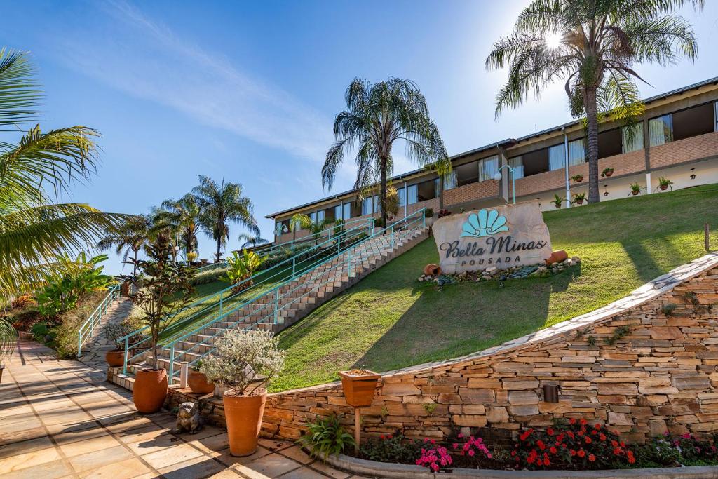 a building with palm trees and a sign on it at BellaMinas Pousada in Guapé