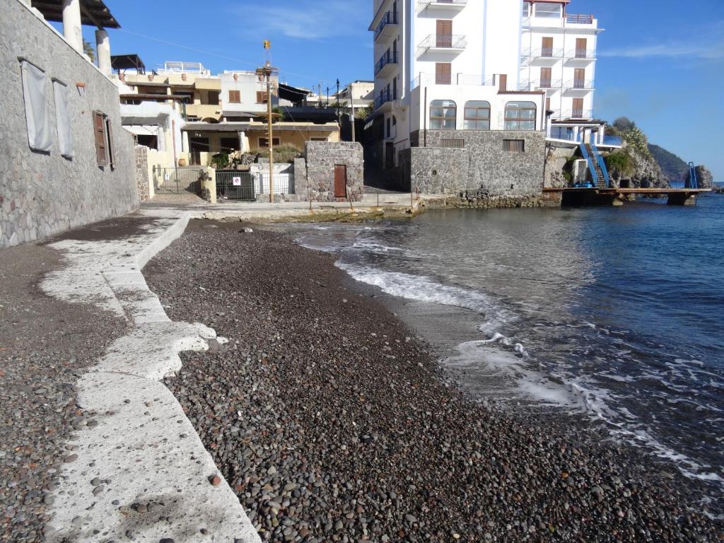 una playa rocosa junto al agua con edificios en Casa Malvasia, en Lipari