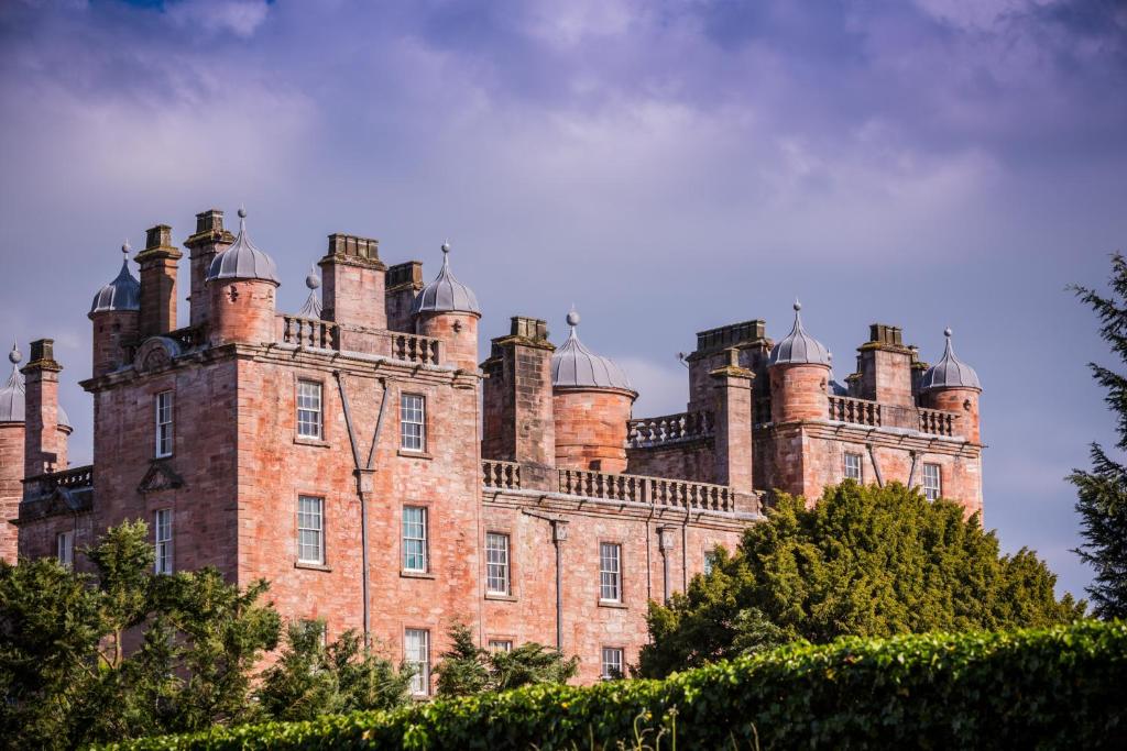 stary zamek z wieloma kominami na górze w obiekcie Stableyard Studio: Drumlanrig Castle w mieście Thornhill