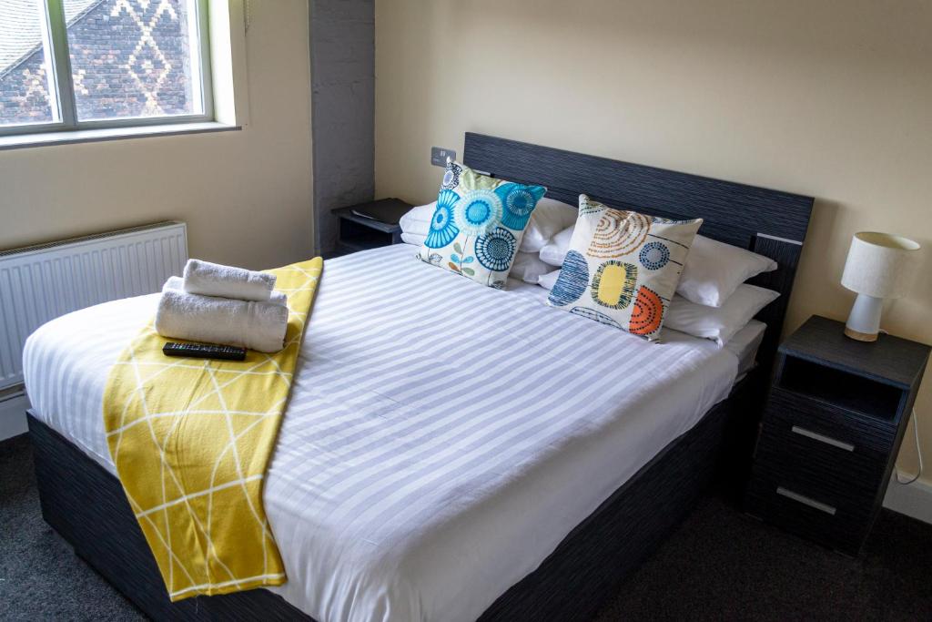um quarto com uma cama grande e almofadas coloridas em Potbank em Stoke-on-Trent