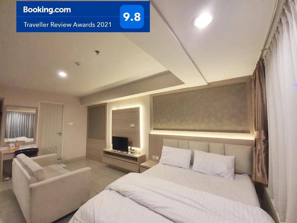 a bedroom with a bed and a couch and a television at Apartemen Grand Kamala Lagoon Studio By Bonzela Property in Bekasi