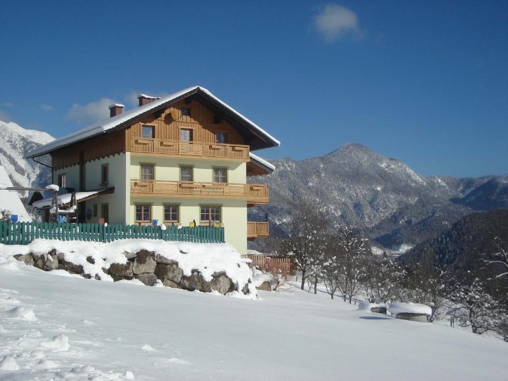una casa en una colina cubierta de nieve frente a una montaña en Familienbauernhof Christa, en Rossleithen