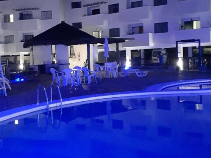 - une piscine avec des chaises et des parasols en face d'un bâtiment dans l'établissement Aparts da Praia Grande 79, à Arraial do Cabo