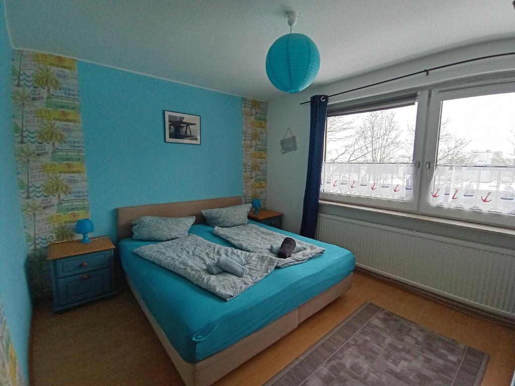 Un dormitorio con una cama con paredes azules y una ventana en Ferienwohnung Leuchtturm mit E-Bike Verleih en Wilhelmshaven