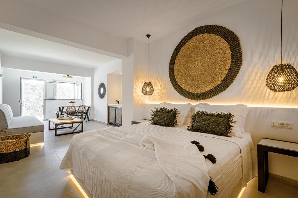a bedroom with a large white bed and a living room at Thealos Santorini in Pyrgos