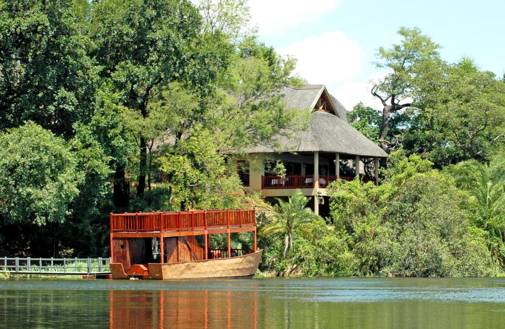 a boat on the water with a house in the background at Divava Okavango Resort & Spa in Bagani