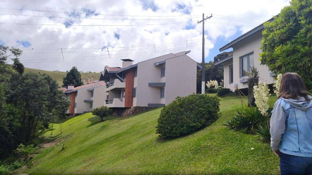 a woman walking down a hill in front of a house at Plaza Inn Week Inn in Campos do Jordão