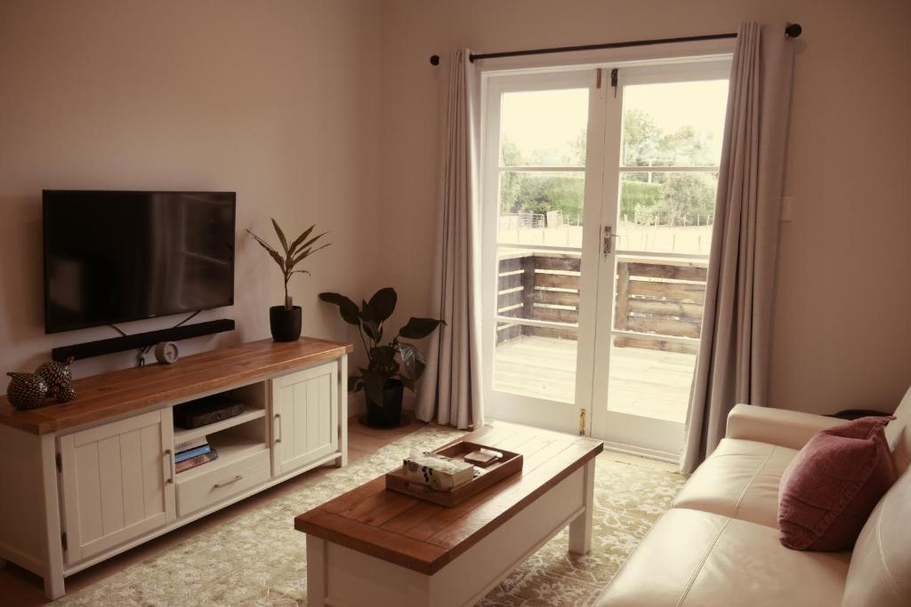 a living room with a couch and a television at Apartment on St Georges in Havelock North