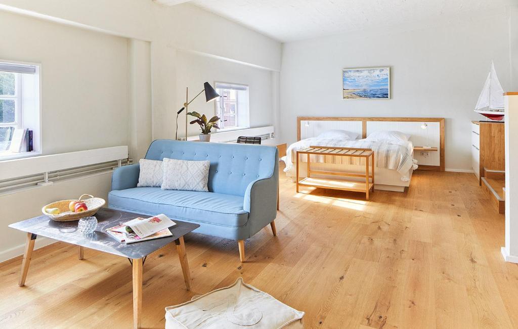 a living room with a blue chair and a bed at Pierspeicher Boardinghouse in Kappeln