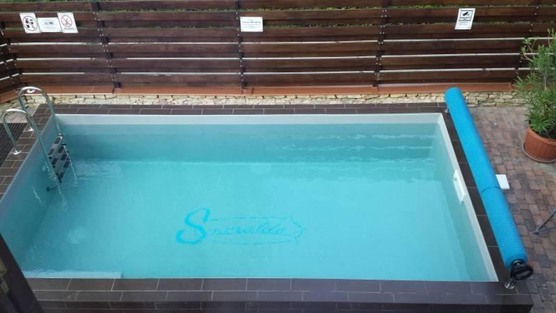 duży niebieski basen przed ławką w obiekcie Apartment- Villa 6 w Siófoku