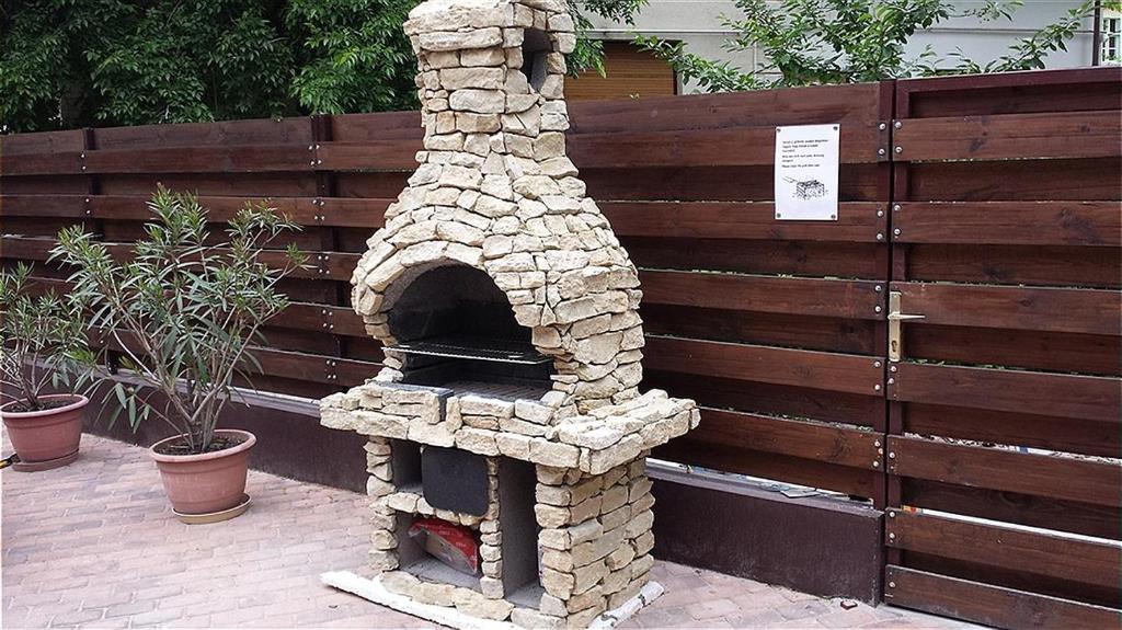 kamienny piec pizzy siedzący obok płotu w obiekcie Apartment- Villa 6 w Siófoku