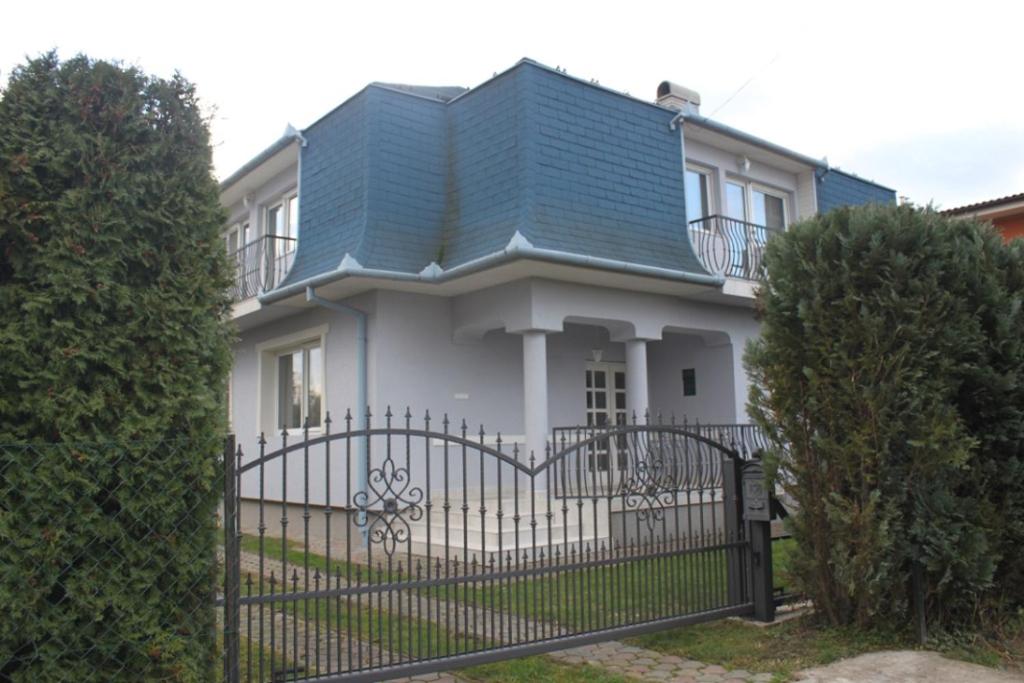 une maison blanche avec un toit bleu et une clôture dans l'établissement Pine Wood Apartment 5, à Zalakaros