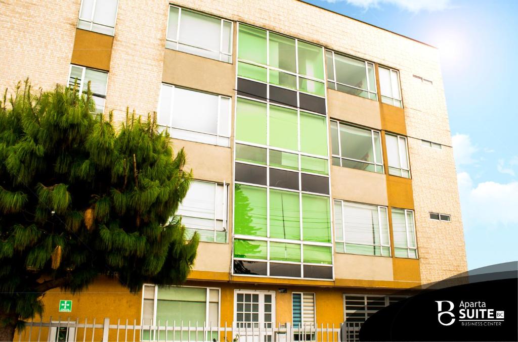 un edificio de apartamentos con un árbol delante de él en Apartasuites Plaza Modelia, en Bogotá
