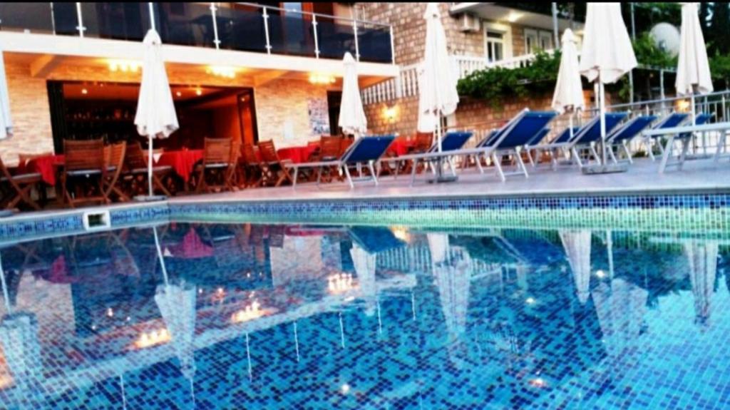 una gran piscina con sillas y sombrillas en Apartments Dragišić, en Sveti Stefan