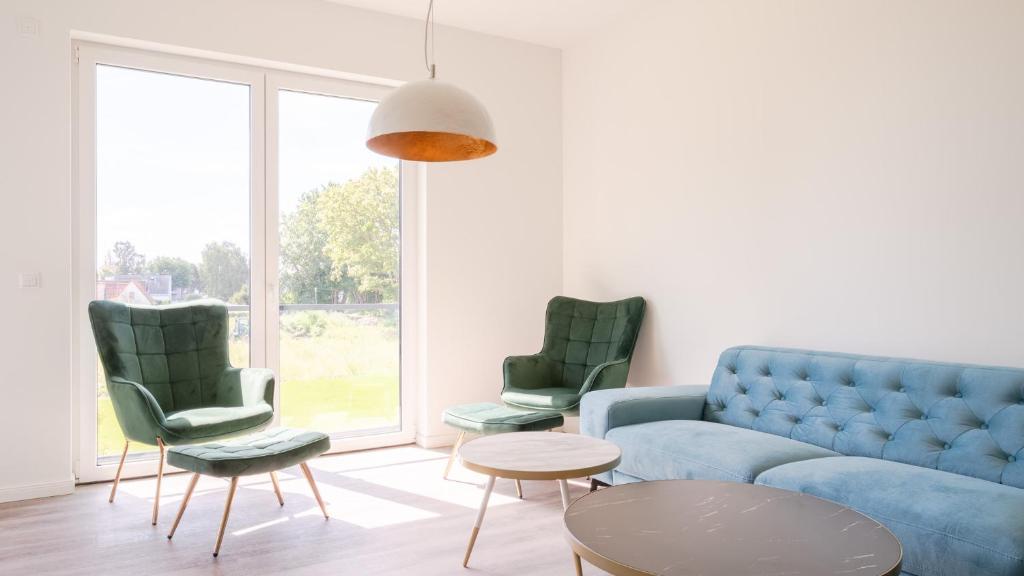 ein Wohnzimmer mit einem blauen Sofa und zwei grünen Stühlen in der Unterkunft Apartmenthaus Wittsande Wittsande 09 in Zingst