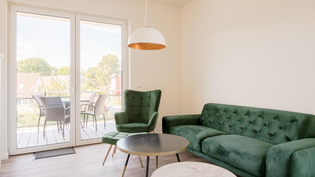 ein Wohnzimmer mit einem grünen Sofa und einem Tisch in der Unterkunft Apartmenthaus Wittsande Wittsande 06 in Zingst