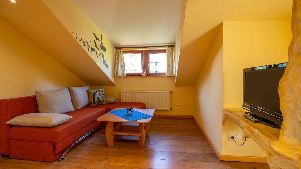 een woonkamer met een rode bank en een tv bij Hexenhaus Kammer in Prerow