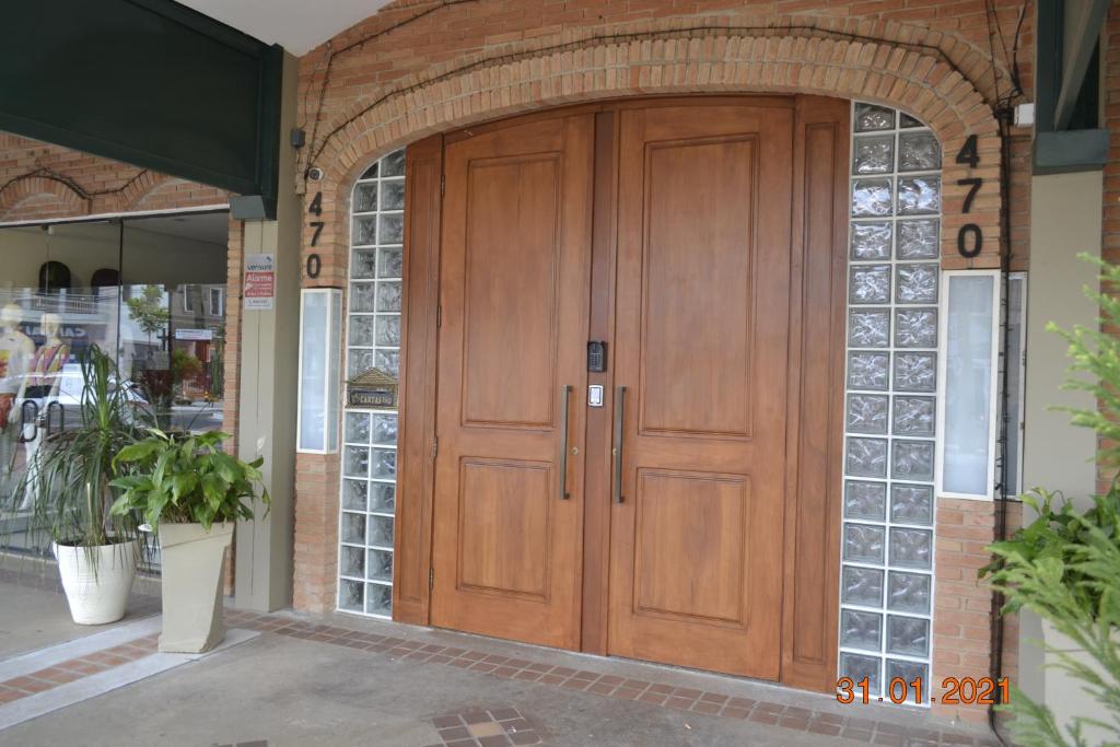 uma grande porta de madeira num edifício de tijolos em Apto Top Centrum Holambra/excelente localização em Holambra