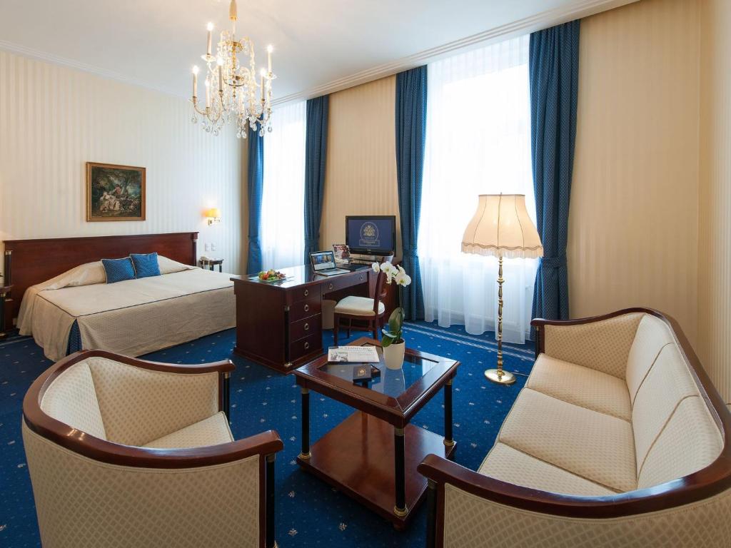 a hotel room with a bed and a table and chairs at Hotel Ambassador in Vienna