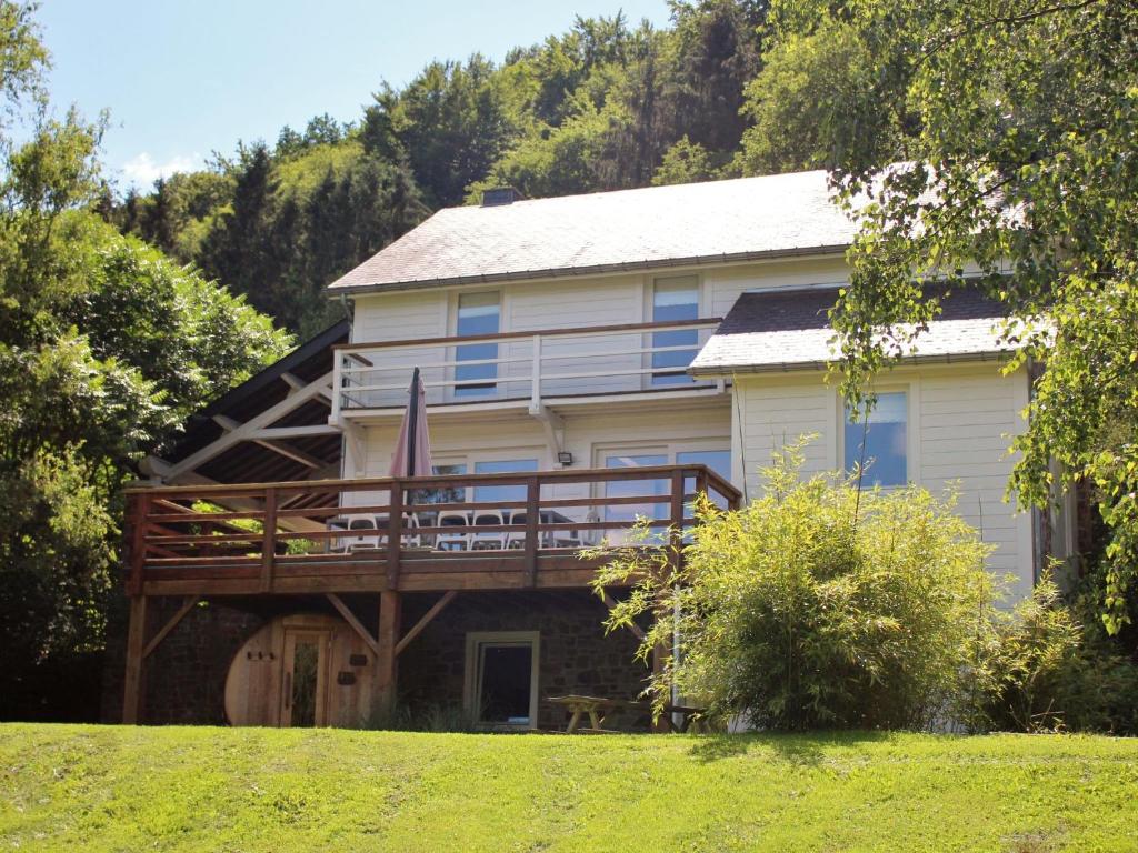 a large white house with a large deck at Spacious Holiday Home in Rendeux with Sauna in Rendeux