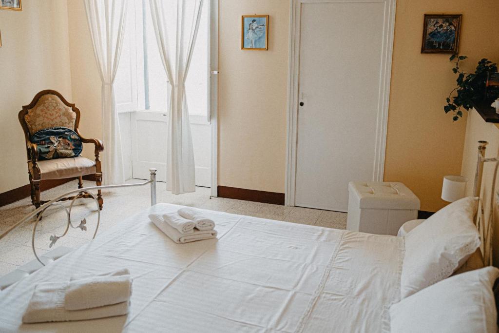 un letto bianco in una stanza con una sedia e una finestra di Piazza Argento a Lecce