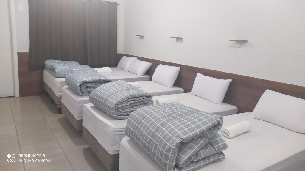 uma fila de camas com almofadas num quarto em Pousada Quarto Suíte Famíliar com ar,frigobar, wi fi e garagem em Aparecida