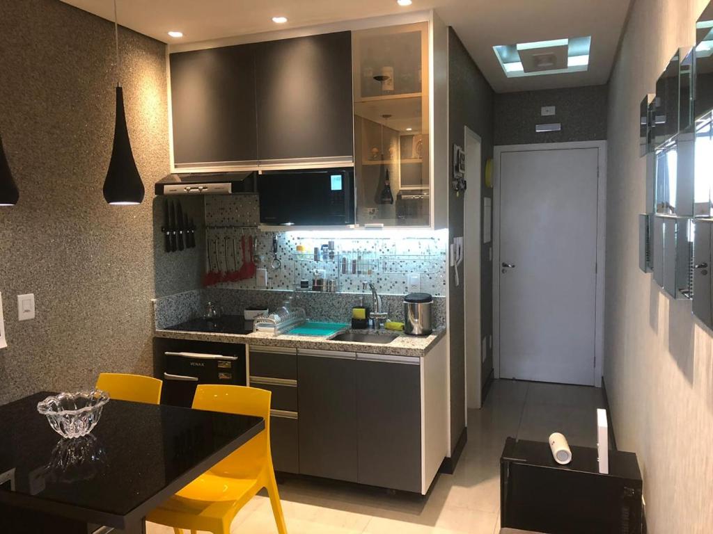 a kitchen with a counter and a table with yellow chairs at Flat Vip 5 Estrelas Granja Vianna Luxuoso e Sofisticado Alto Padrão Animália Park! in Cotia