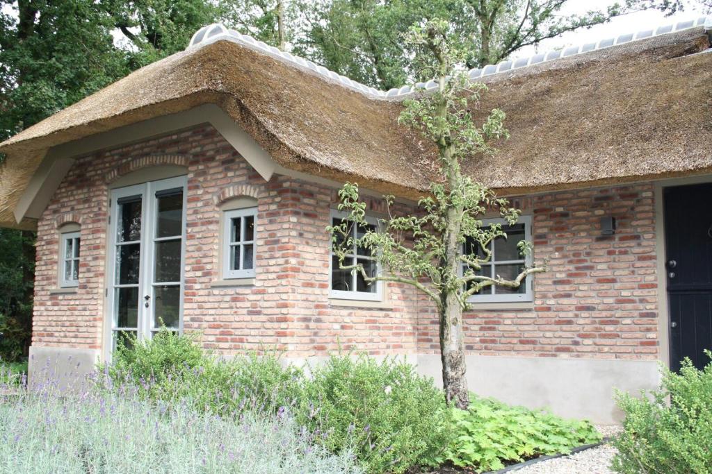 een klein bakstenen huis met een rieten dak bij Vlindervallei 2p in Ermelo