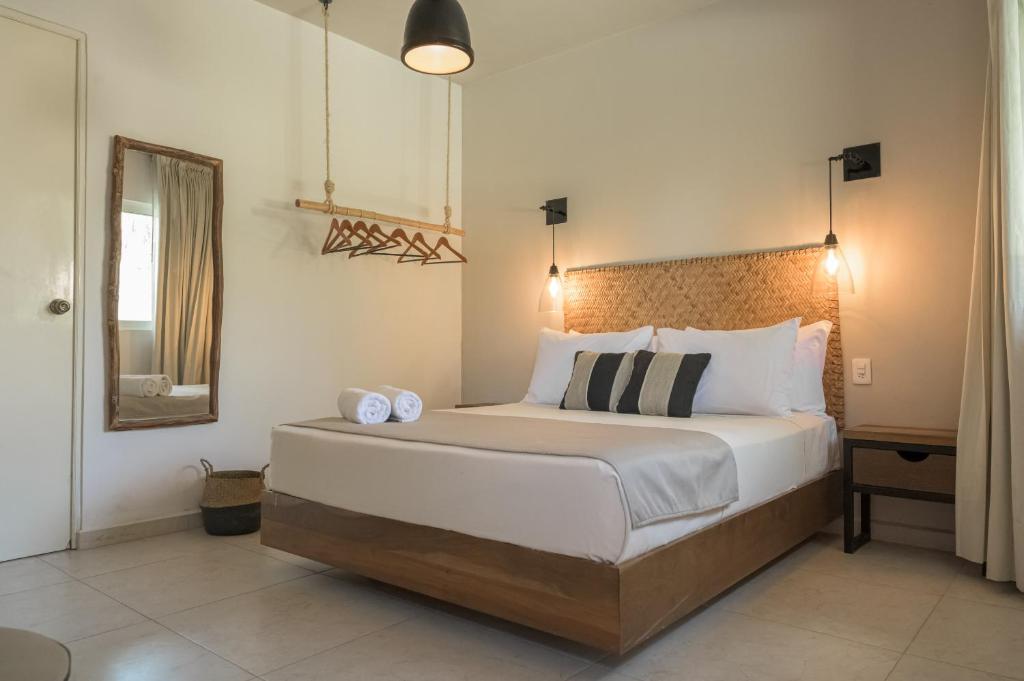 1 dormitorio con 1 cama grande y espejo en Agam Hotel en Bacalar