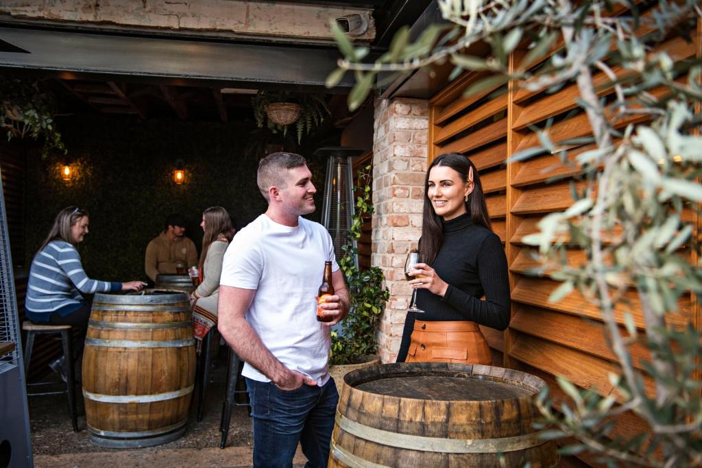 un hombre y una mujer parados junto a barriles de vino en The Woolpack Hotel, en Mudgee
