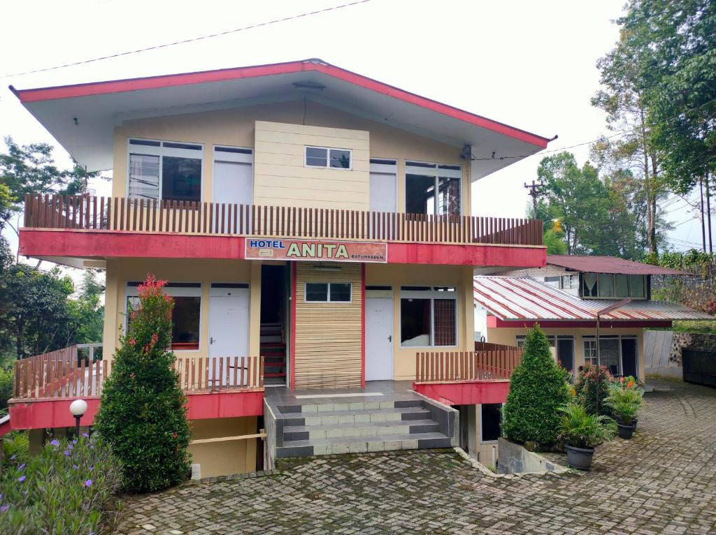 a house with a red and white at Hotel Anita Baturaden Mitra RedDoorz in Baturaden