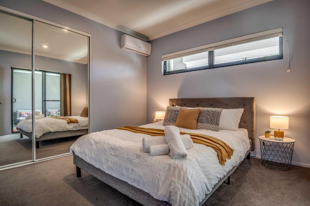 a bedroom with a large bed and a mirror at Maylands Boutique Apartments in Perth