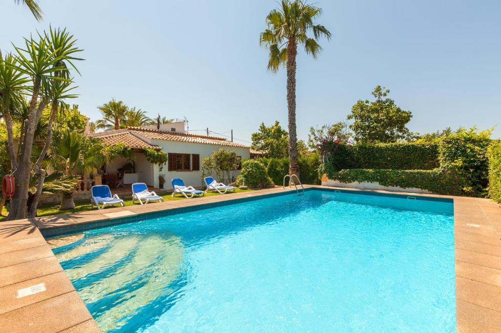 a swimming pool with two chairs and a house at Cal Roma in Pollença