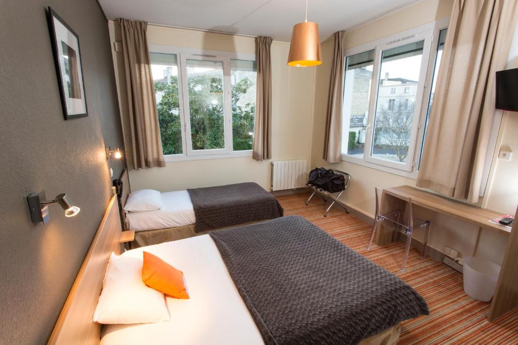 um quarto de hotel com duas camas e duas janelas em Brit Hôtel du Parc Niort Centre-Parking gratuit em Niort