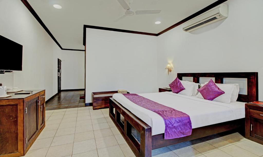 1 dormitorio con 1 cama grande y TV en Treebo Tryst Travancore Palace Cherthala en Alleppey