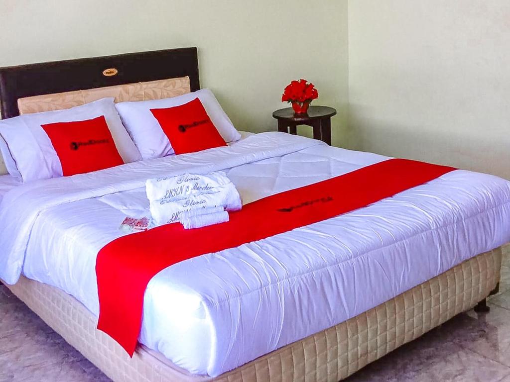 a large bed with a red and white blanket on it at RedDoorz near Reremi Pemancar Manokwari in Manokwari
