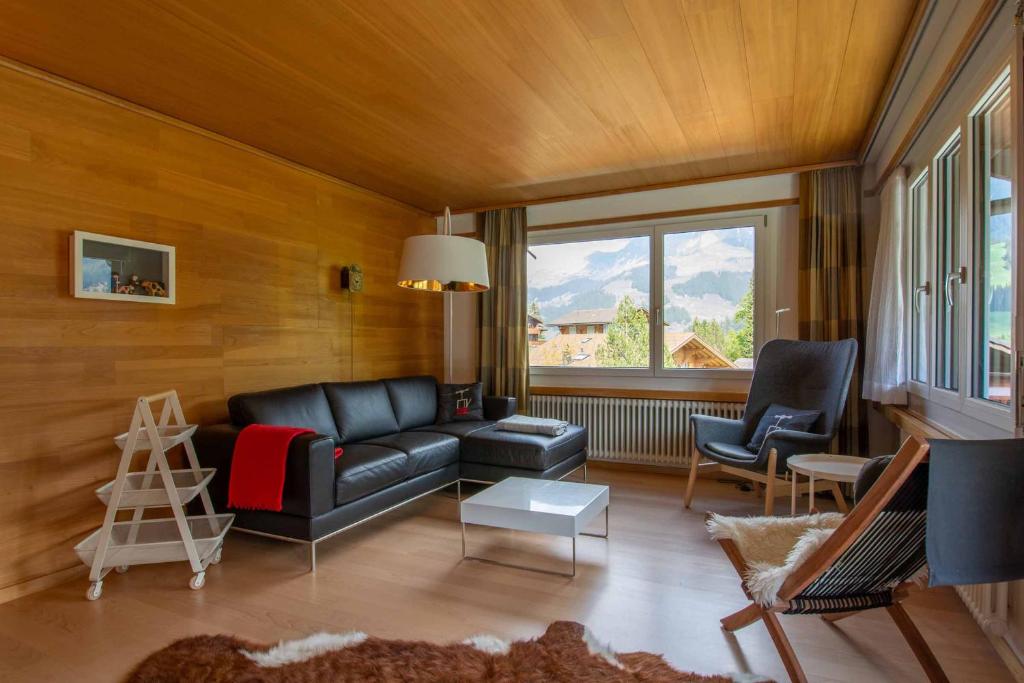 a living room with a black leather couch and chairs at Baldrian C14 in Adelboden