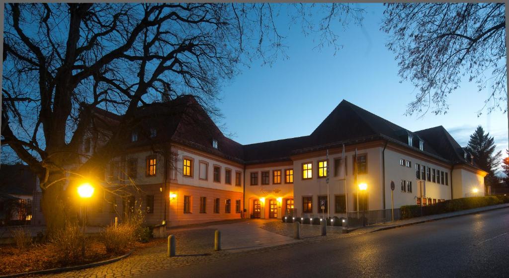 a large white building with lights on a street at Klosterbräuhaus Ursberg in Ursberg