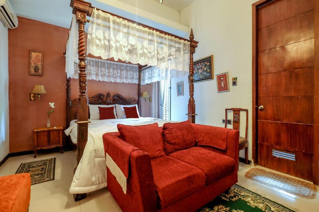 a bedroom with a canopy bed and a red couch at Buminanienie Guesthouse Bandung in Bandung
