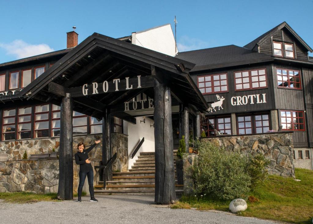 a woman standing in front of a building at Grotli H&oslash;yfjellshotell in Grotli