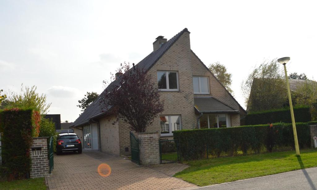 a house with a car parked in the driveway at Villa Josiane in Oostduinkerke