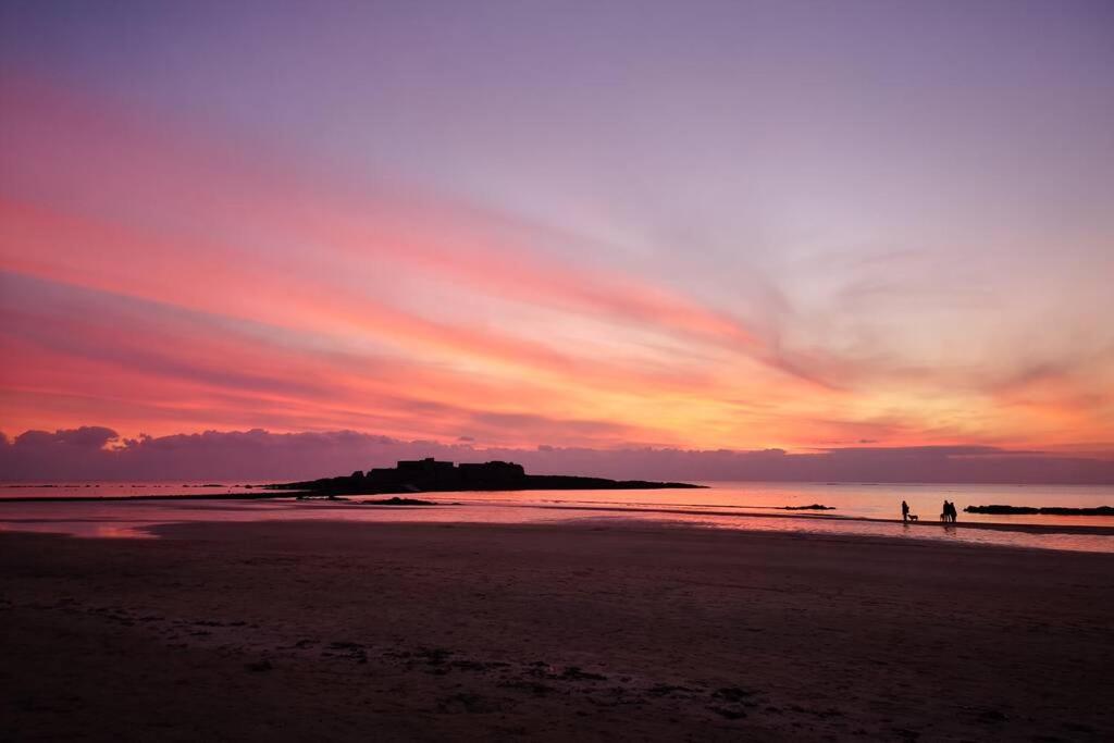 zwei Menschen, die bei Sonnenuntergang am Strand spazieren gehen in der Unterkunft L'horizon 2 - bord de mer in Ploemeur