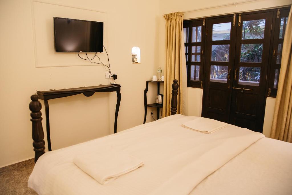 a bedroom with a bed and a tv on the wall at Feliz Arambol in Arambol