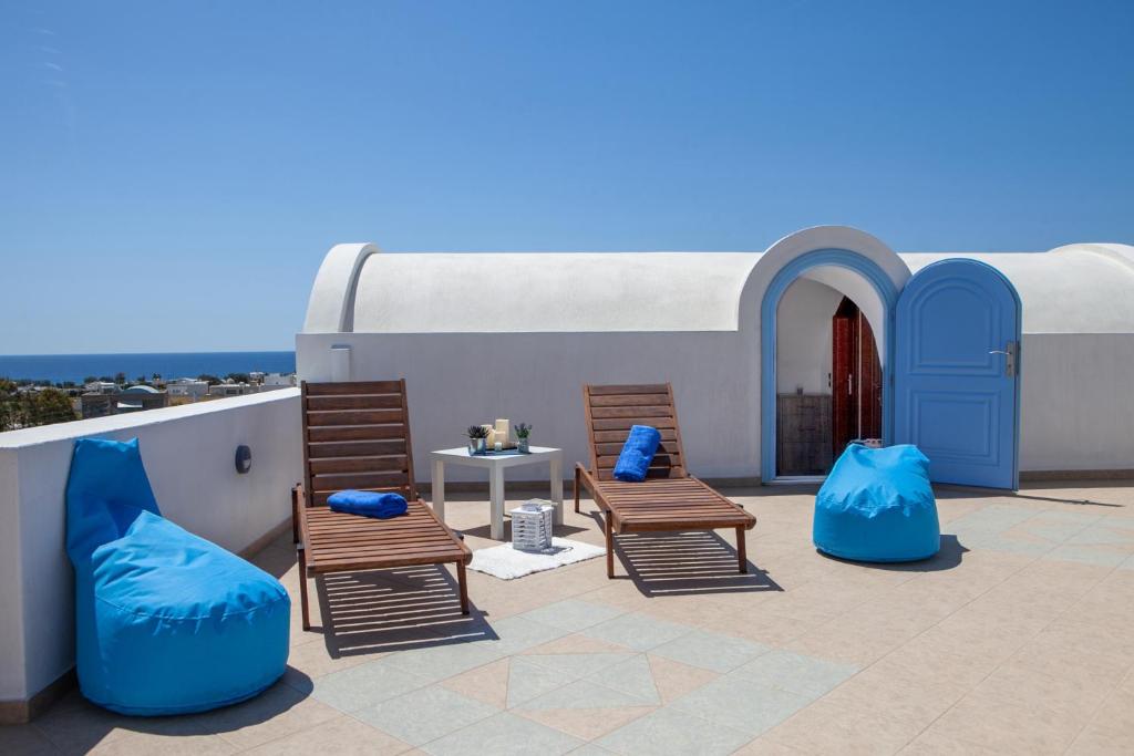 a patio with two chairs and a table on a roof at Sunrise Apartment Santorini in Emporio Santorini