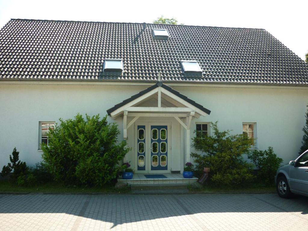 a white house with a blue door at Pension Dachgeschosswohnung in Bastorf