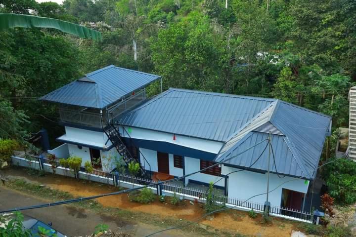 a house with two blue roofs and a fence at Eden Homestay Idukki in Idukki