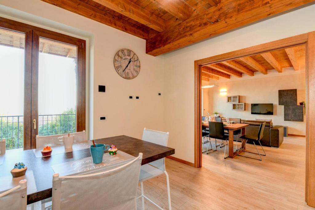 uma sala de jantar e sala de estar com um relógio na parede em Villa Sinfonia em Polpenazze del Garda