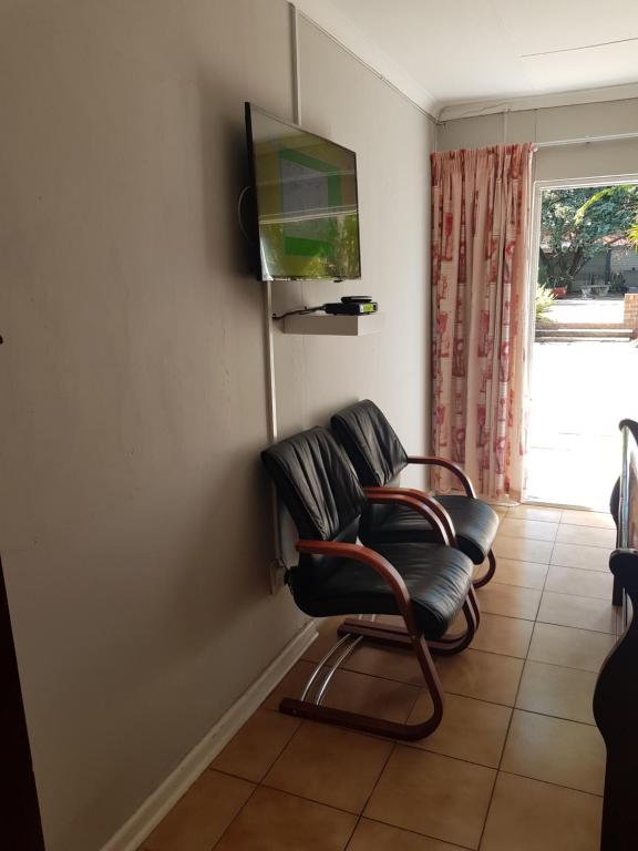 a chair in a room with a television on the wall at AGT Guesthouse in Vryheid