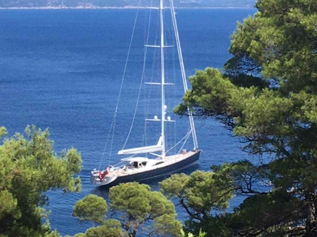 a sailboat on the water with trees in the foreground at Apartments Matusko in Saplunara