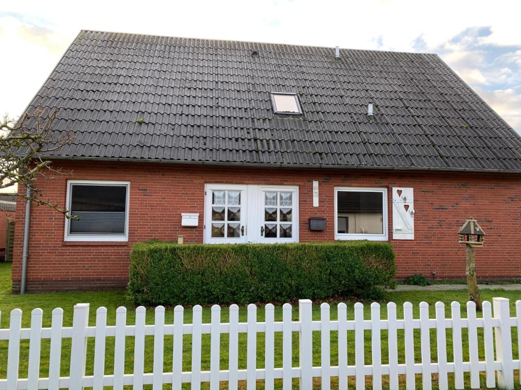 a red brick house with a white fence at Ferienwohnung_25 in Uphusum